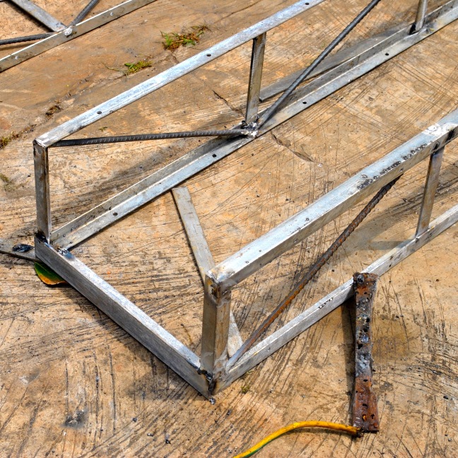 on flat and level ground surface, weld pair of 2d trusses together with 1-1/2in angle bar at top and bottom corners.